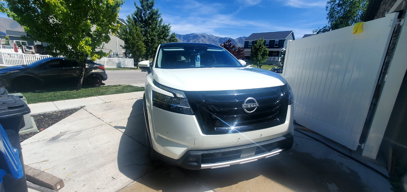 White Nissan Pathfinder SUV after wash — front view with mountains in background